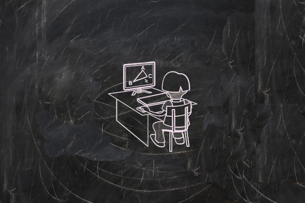 Image of a person sat in front of a computer on a chalk board
